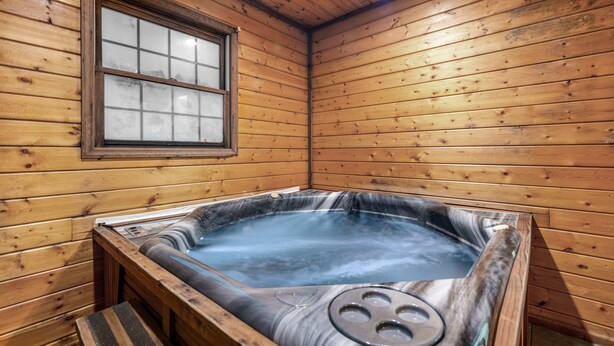Une cabane en bois avec un bain à remous, une fenêtre et un banc.