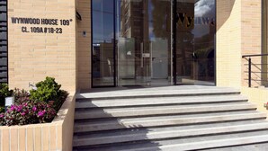 Ein Gebäudeeingang mit Glastür und Stufen, die hinaufführen. Ein Schild weist 'Wynwood House 109' und 'CL. 109A #18-23' aus.