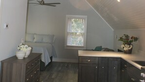 A kitchen with wooden cabinets, a countertop, and a ceiling fan. - Norah's Nest 
"Step into your own private retreat!" (WOODSTOCK)