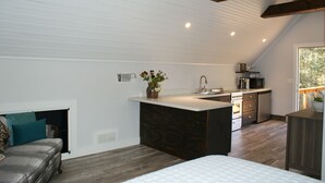 A modern loft-style bedroom with a large bed, a built-in desk, and a kitchenette. - Norah's Nest 
"Step into your own private retreat!" (WOODSTOCK)