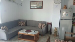 A living room with a grey sofa, a wooden coffee table, a clock, a refrigerator, and a vase. - Vacation rentals in Bejaia (Béjaïa)