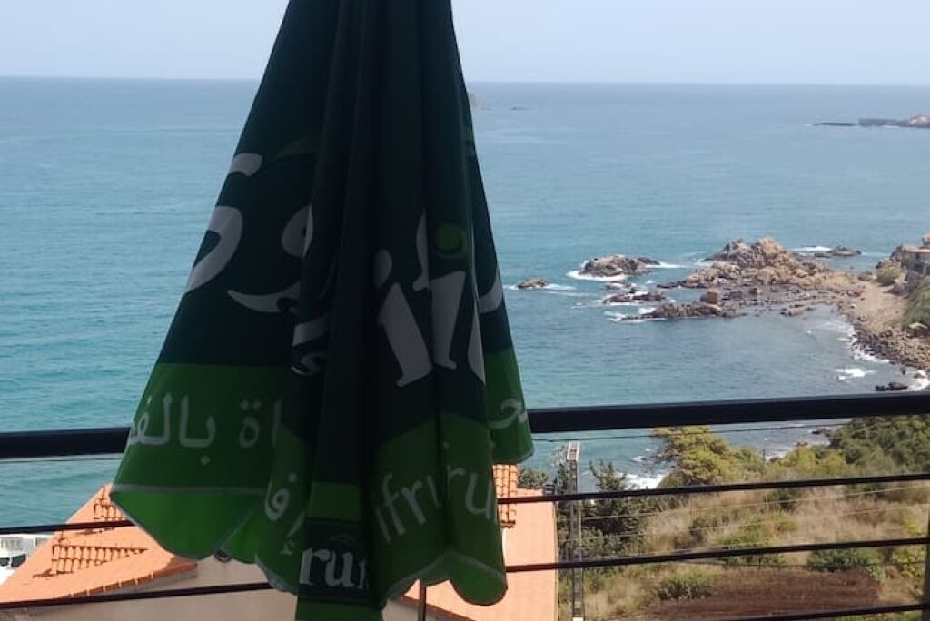 En balkon med udsigt over havet og en klippefyldt kystlinje.
