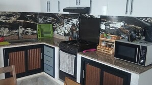 A kitchen with granite countertops, a gas stove, a microwave, and wooden cabinets. - Vacation rentals in Bejaia (Béjaïa)