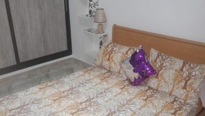 A bed with a patterned bedspread, a wooden headboard, and a decorative pillow. - Vacation rentals in Bejaia (Béjaïa)