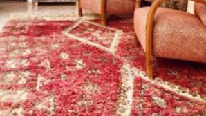 A cozy living room with a red patterned rug, wooden furniture, and a staircase leading to another level. - Riad dar Tayri (Marrakech)