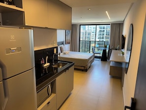 A modern hotel room with a kitchenette, a bed, a small dining area, and a balcony with a city view. - Way Tambaú Suites (João Pessoa)