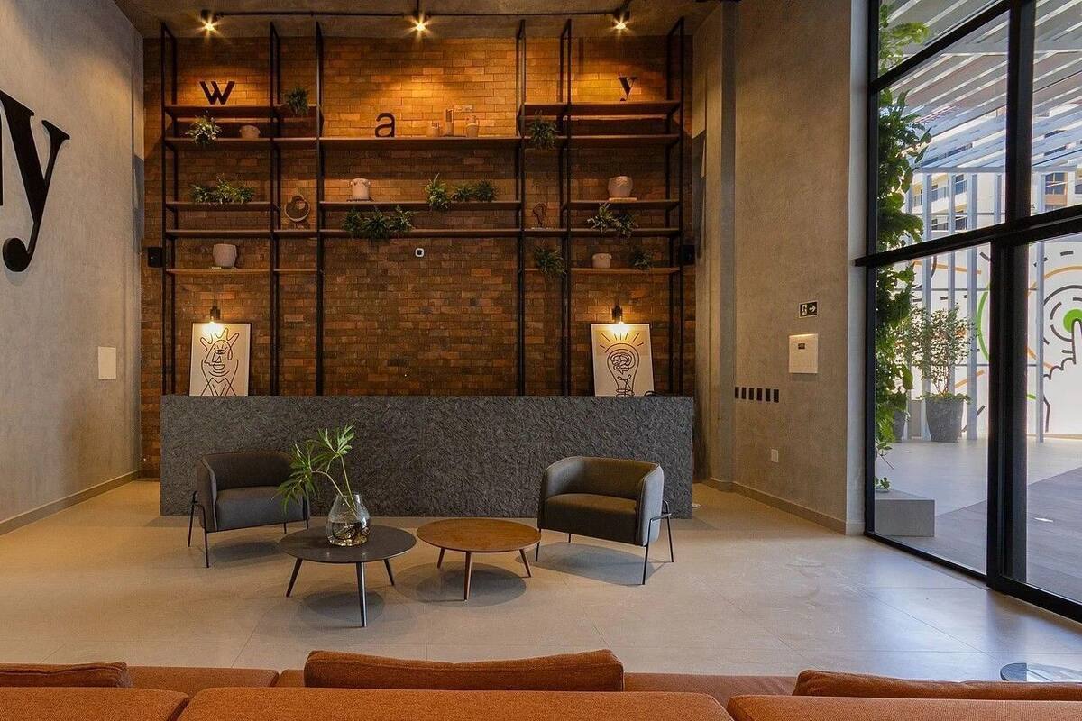 Un hall d'entrée moderne avec un mur en briques, un comptoir de réception, deux canapés, une table basse et une grande fenêtre.