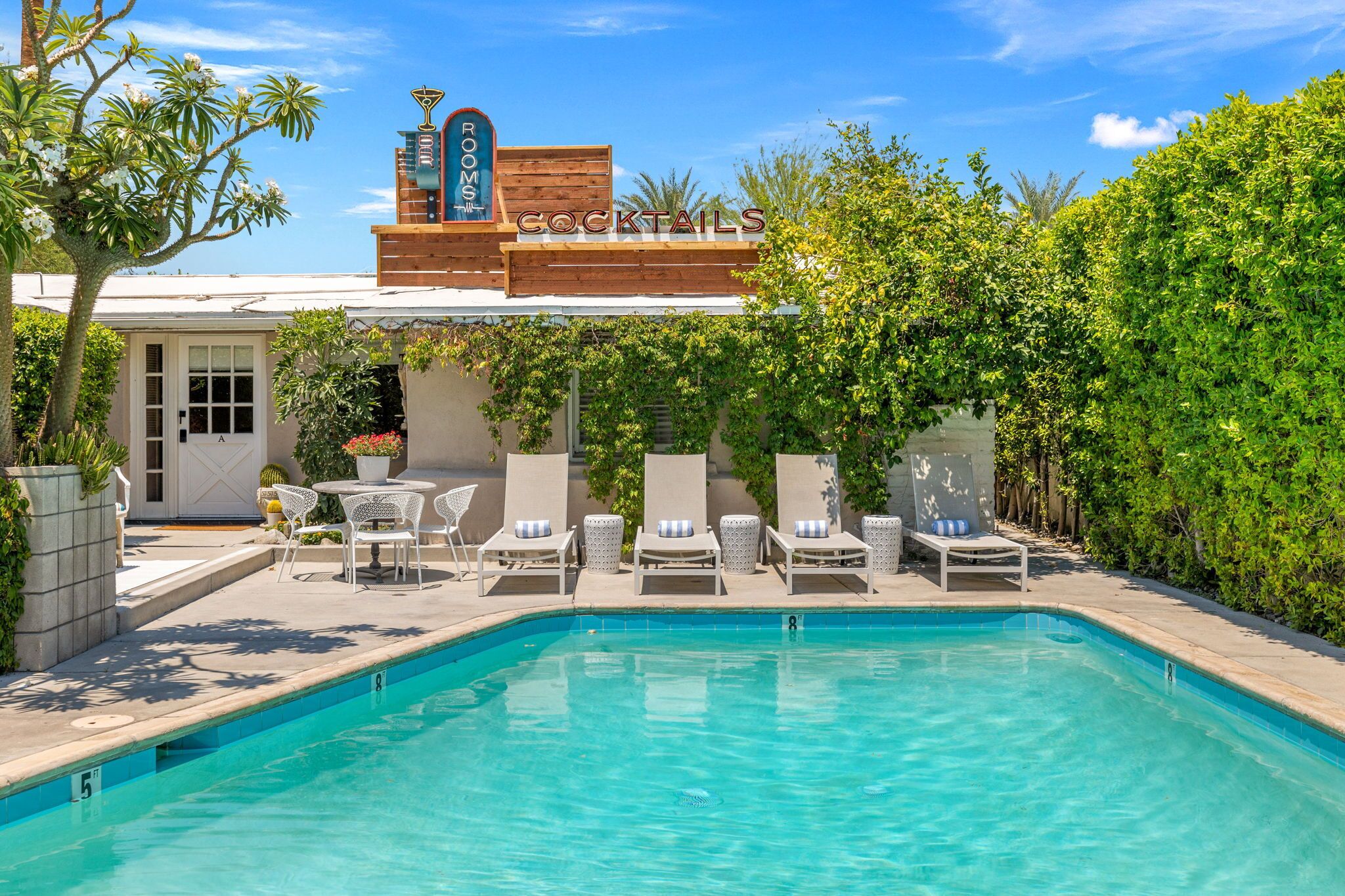 A pool area with lounge chairs and a sign for 'COCKTAILS'.