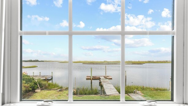 A view through a window with a grid pattern, overlooking a calm lake with docks and grassy areas. - Deep Water Access, Best Waterway Views, Pet-Friendly (Surf City)