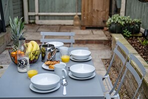 A table set for breakfast with a bottle of Stonehouse milk, a basket of bananas, a pineapple, and a glass of orange juice. - Pet-friendly Stonehouse cottage, minutes to the M5 (Gloucestershire)