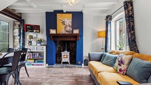 Una sala de estar acogedora con chimenea, un sofá, una mesa de comedor con sillas y una estantería.