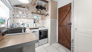 Una cocina con encimera de madera, estufa, lavamanos y puerta de madera.