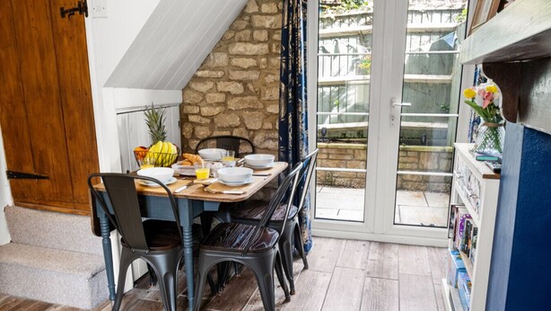 Un comedor con pared de piedra, puerta de madera y puerta de cristal que da al exterior.