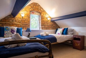 A bedroom with two beds, a brick wall, a window, and a radiator. - Pet-friendly Stonehouse cottage, minutes to the M5 (Gloucestershire)
