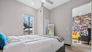 Ein Schlafzimmer mit einem Bett, einem großen Spiegel, einem Deckenventilator und einer Wand mit einer Bildercollage.