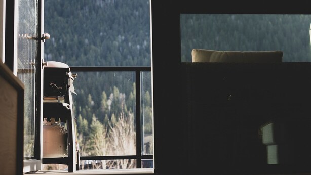 A room with a large window overlooking a mountainous landscape. - Condo with Mountain Views and Rooftop Hot Tub! (Revelstoke)