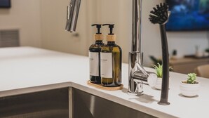 A modern kitchen with a stainless steel sink, a faucet, and two bottles of soap. - Condo with Mountain Views and Rooftop Hot Tub! (Revelstoke)