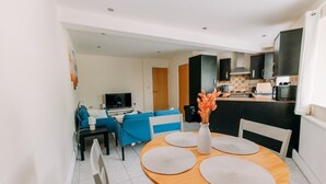 A modern kitchen with dark cabinets, a microwave, and a sink. - Chic 3 Bed Flat on Harbour Way (Kent)