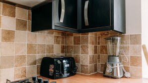 A kitchen with a toaster, a blender, and a gas stove. - Chic 3 Bed Flat on Harbour Way (Kent)