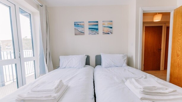 A double room with two beds, a balcony, and a view of the sea. - Chic 3 Bed Flat on Harbour Way (Kent)
