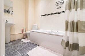 A bathroom with a white sink, toilet, and bathtub. There is a mirror above the sink, and a shower curtain is partially visible. - 2 Bedroom Flat on Harbour Way! (Kent)