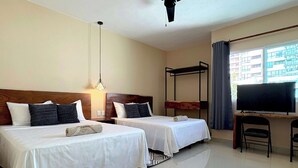 Ett hotellrum med två sängar, ett skrivbord, en TV och en takfläkt.