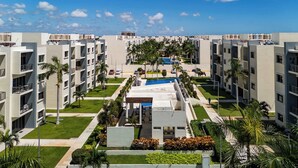 Un complexe hôtelier moderne composé de plusieurs bâtiments, doté d’une piscine centrale et d’espaces verts bien entretenus.