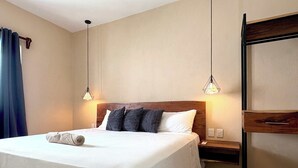 Un lit bien fait, avec une couette blanche et des oreillers, une tête de lit en bois et deux tables de chevet avec des lampes.