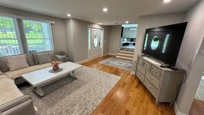 A living room with a sofa, coffee table, TV, and a staircase leading to another level. - Fantastic 5-bedroom house with a pool in charming Clintondale (Clintondale)