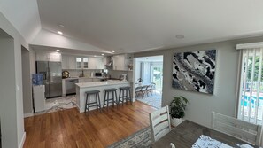 A modern kitchen with white cabinets, a marble island, and a dining area with a table and chairs. - Fantastic 5-bedroom house with a pool in charming Clintondale (Clintondale)