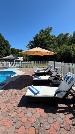 A poolside area with lounge chairs, a pool, and a white picket fence. - Fantastic 5-bedroom house with a pool in charming Clintondale (Clintondale)