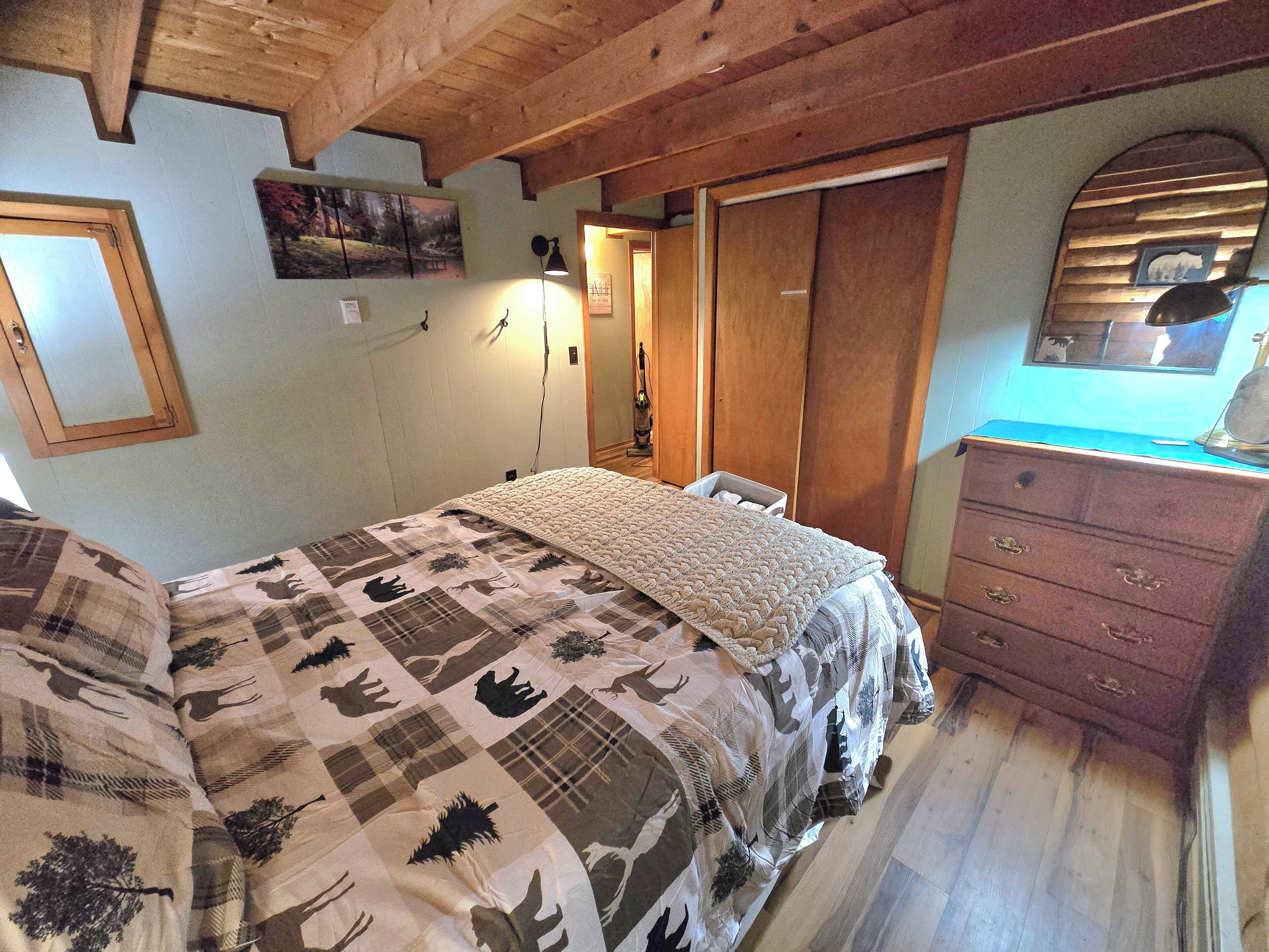 A bedroom with a bed, wooden wardrobe, and a dresser.