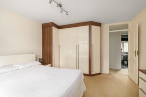A bedroom with a bed, wardrobe, and a door leading to a bathroom. - Spacious 2 Bed Home with Parking Near City Centre (West Midlands)