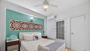 Een slaapkamer met een bed, nachtkastje, wanddecoratie, plafondventilator en een kledingkast.