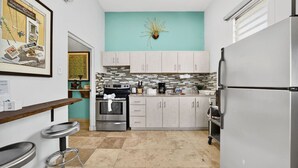 A compact kitchen with a teal accent wall, a stainless steel refrigerator, and a tiled backsplash. - Renovated Retreat by Condado Lagoon and Nightlife (San Juan)