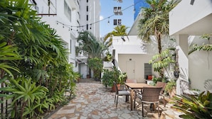 A courtyard with a stone-tiled floor, a table with chairs, and potted plants. - Renovated Retreat by Condado Lagoon and Nightlife (San Juan)