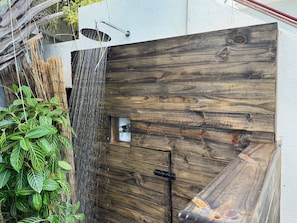 A wooden gate with a metal latch, a small window, and a vertical water feature. - Condado 4BR for Groups | Separate King Studio (San Juan)