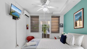 A bedroom with a bed, a TV, a ceiling fan, and a window with blinds. - Condado Queen Studio, Near Beach & Dining (San Juan)
