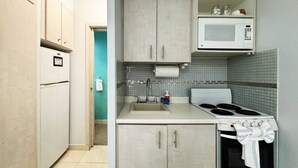 A compact kitchen with a microwave, stove, and sink. - Condado Queen Studio, Near Beach & Dining (San Juan)