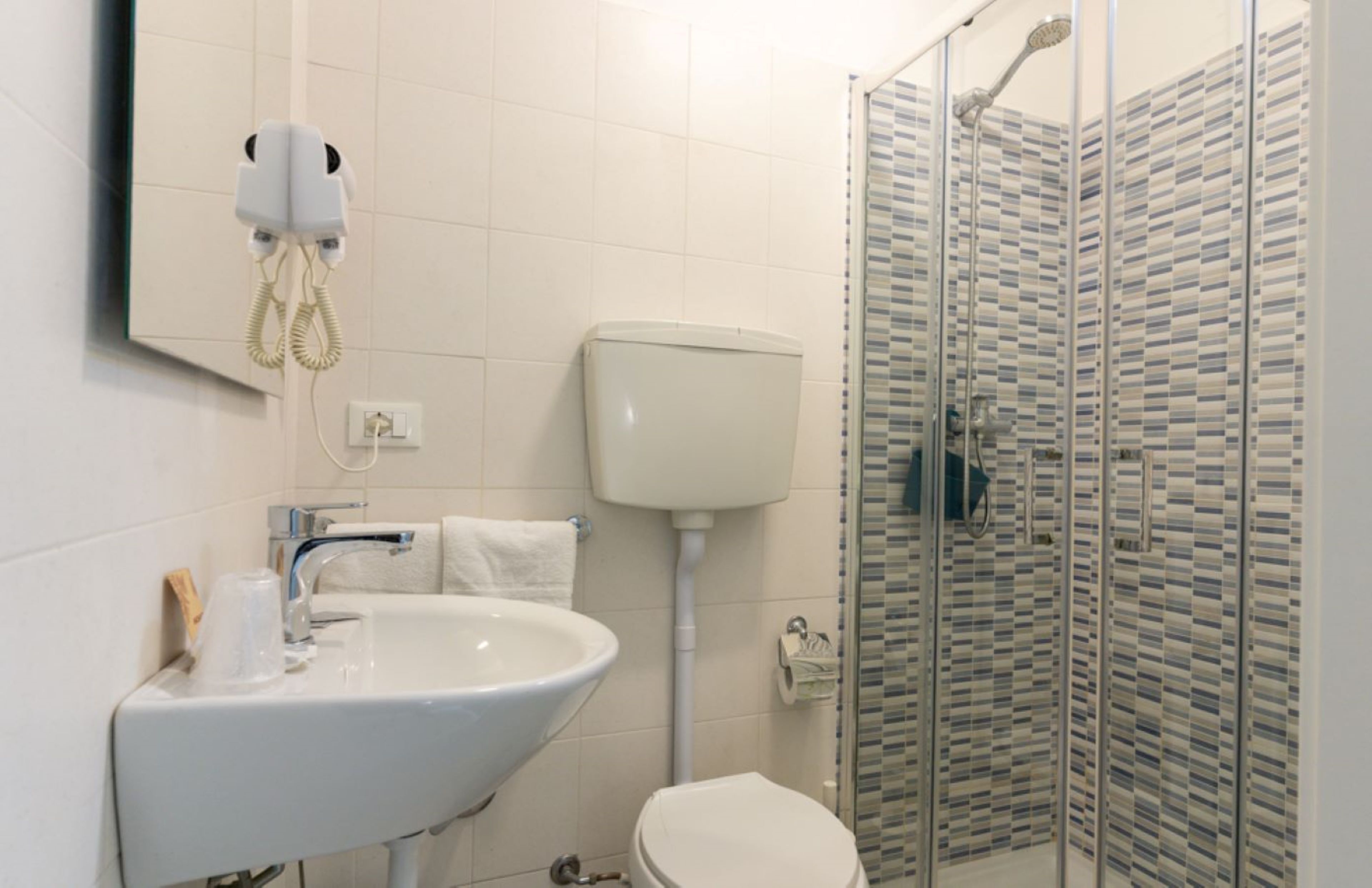 A bathroom with a white sink, toilet, and glass shower enclosure.