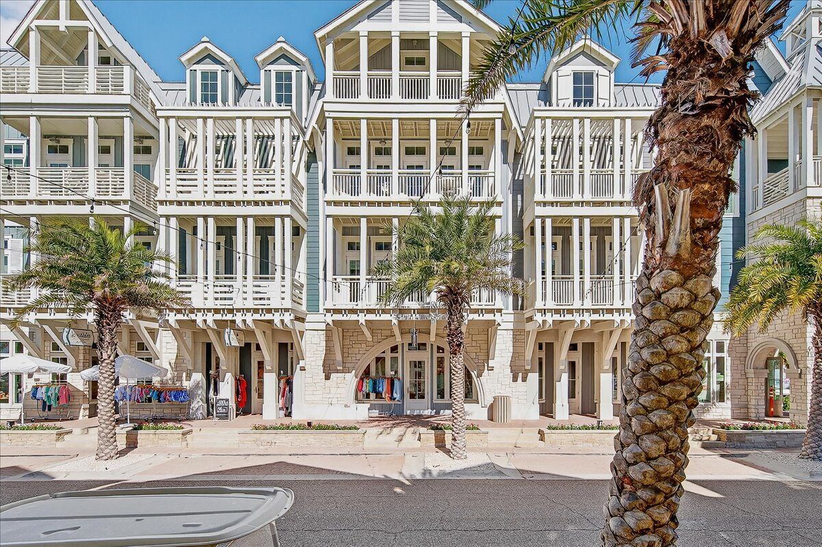 Ein Strandhotel mit mehreren Balkonen, Palmen und blauem Himmel.