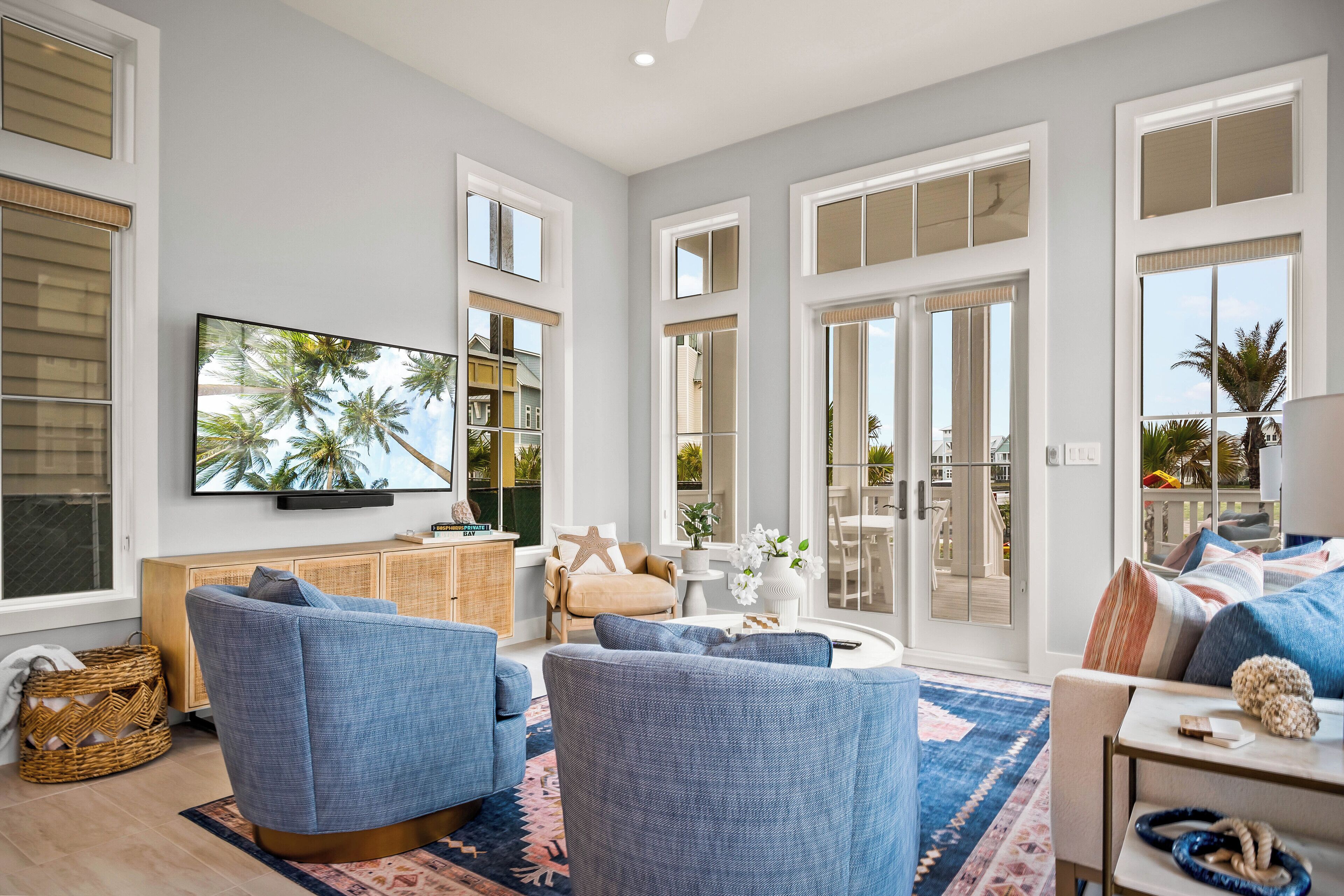 A spacious living room with a large flat-screen TV, comfortable seating, and a view of the outdoors.