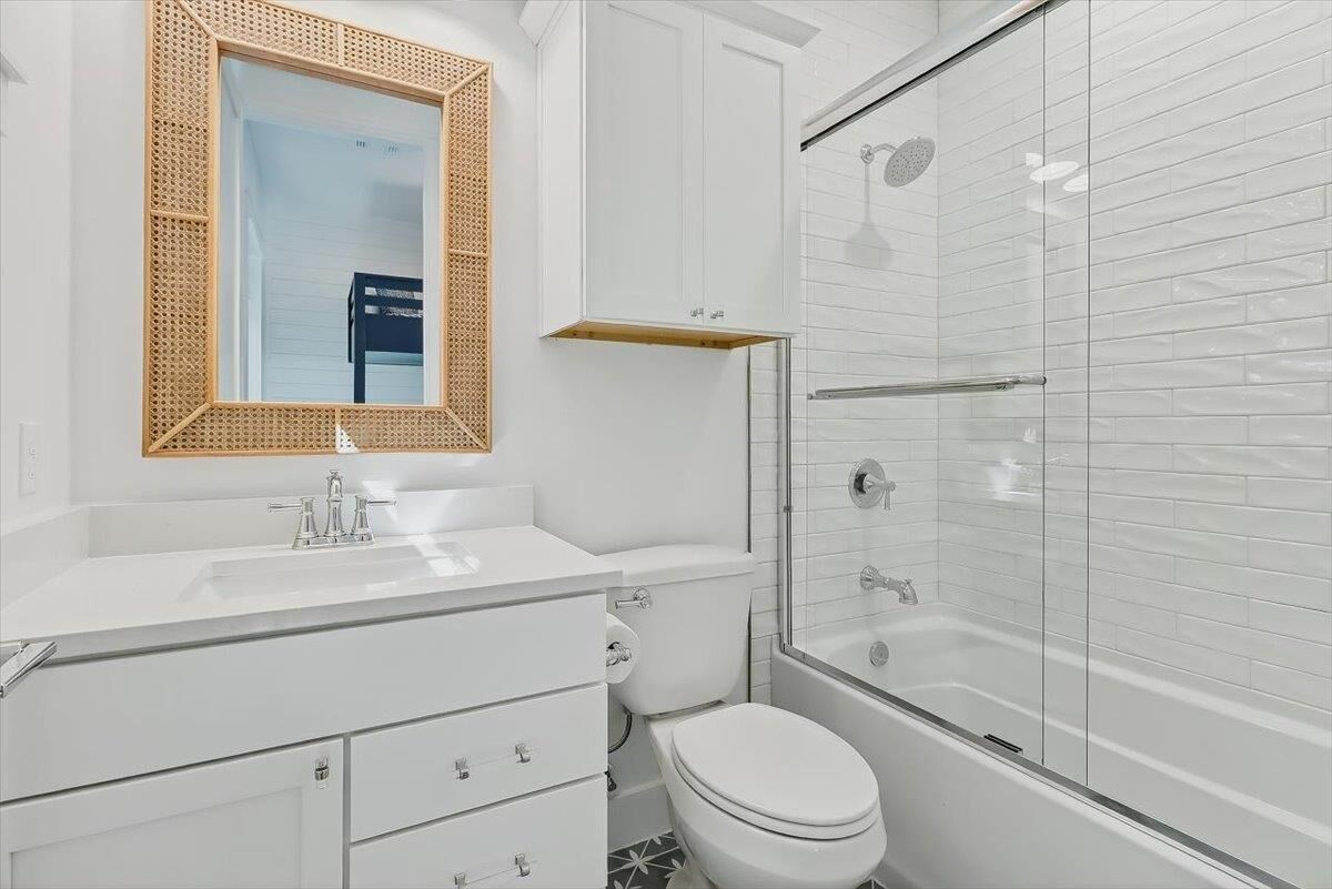 Une salle de bain moderne avec un lavabo blanc, un miroir, des toilettes et une douche à parois de verre.