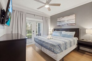 Ein Schlafzimmer mit einem Bett, einem Deckenventilator, einem Fernseher und einem Bild an der Wand.