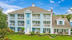 A multi-story building with balconies, a covered patio area, and a well-maintained lawn. - First Floor Resort Condo Poolside Oasis (Kissimmee)