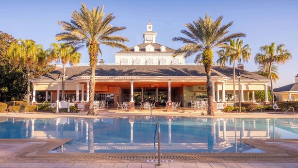 A hotel with a pool, palm trees, and a covered patio area. - First Floor Resort Condo Poolside Oasis (Kissimmee)