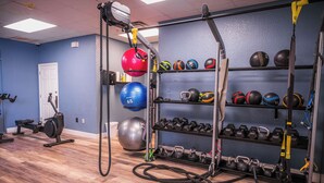 A gym with exercise equipment, including a stationary bike, kettlebells, medicine balls, and a rack of dumbbells. - First Floor Resort Condo Poolside Oasis (Kissimmee)