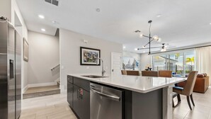 A modern kitchen with a large island, stainless steel appliances, and a dining area with a view. - Poolside Retreat at Reunion Resort Steps from the Water & Minutes to Disney (Kissimmee)