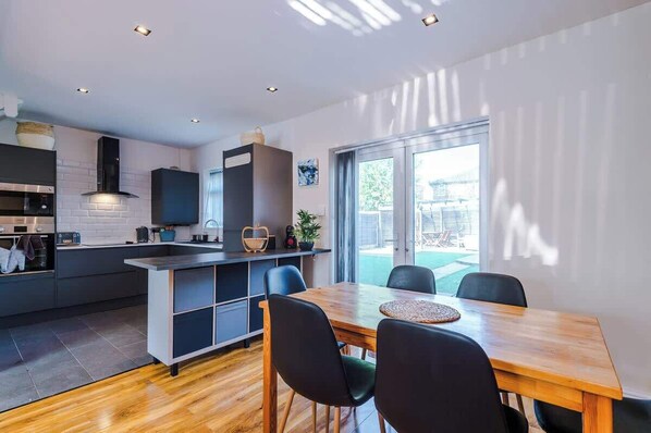 A modern kitchen with a dining area, built-in appliances, and a large window.