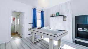 Una mesa de billar en una habitación con paredes blancas y suelo de madera.